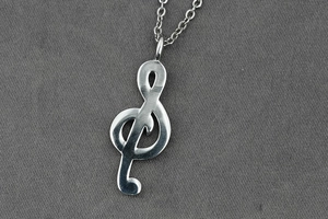 Close-up of a silver treble clef musical note pendant on a sleek stainless steel chain