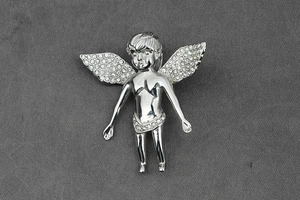 Détail d'un pendentif ange argenté serti de strass brillants sur tissu foncé