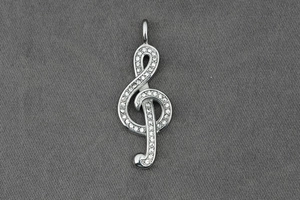 Macro detail of a silver treble clef pendant with sparkling white rhinestones and bail