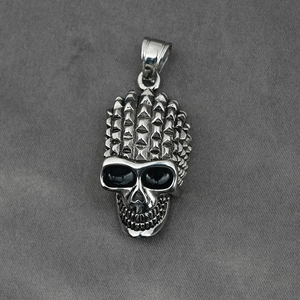 Punk style silver skull pendant with spiked top and deep eye sockets on textured fabric