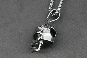 Macro side view of polished stainless steel punk skull pendant with ring chain links