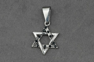 Détail du pendentif hexagramme avec pierres noires sur un fond de tissu gris texturé