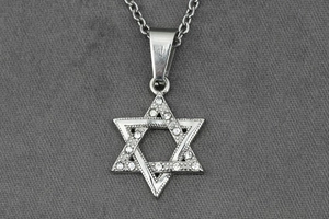 Gros plan d'un pendentif hexagramme argenté orné de strass sur une longue chaîne de pull