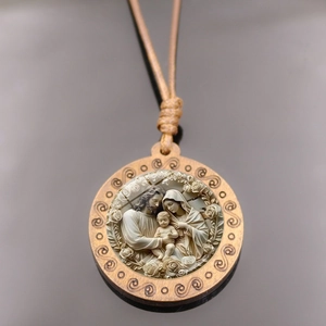 Macro d'un pendentif en bois avec relief de la Sainte Famille et sculptures florales fines