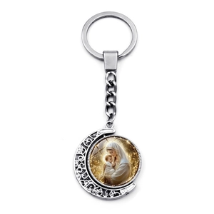 Macro view of rotating silver crescent moon keychain with Virgin Mary religious pendant