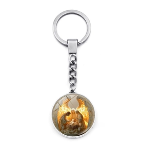 Detail view of a silver religious keychain featuring a nativity scene with golden wings