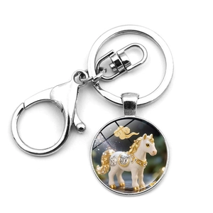 Detail of metal zodiac keychain showing white horse pendant with golden lobster clasp