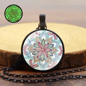 Detailed view of mandala pendant with green luminous effect and black necklace chain