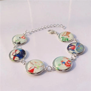 Bracelet de Noël argenté avec des breloques en verre représentant le Père Noël et un bonhomme