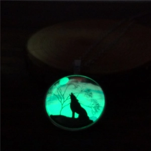 Detailed view of the glowing wolf silhouette pendant necklace in a dark setting