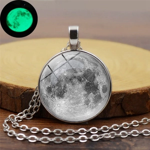 Détail du collier pendentif lune avec effet lumineux nocturne sur surface en bois