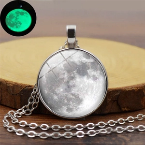 Détail du collier pendentif lune avec orbe en verre luminescent sur bois rustique