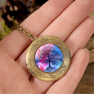 Vintage bronze Tree of Life locket necklace with colorful nebula glass dome held by hand