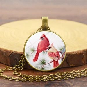 Dettaglio della collana in bronzo vintage con uccelli cardinali e ciondolo in vetro