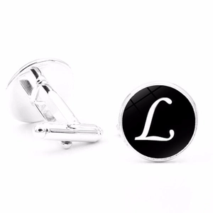 Close-up of silver-tone cufflinks featuring a polished black disk and white letter L detail