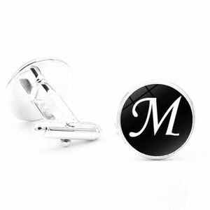 Detailed view of silver men's cufflinks featuring a black round base with a white letter M