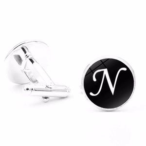 Detail view of silver cufflinks featuring white letter N on black round face