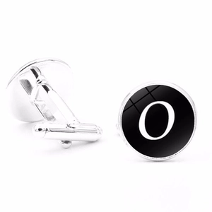 Close-up of silver alphabet cufflinks with letter O on black round glass face