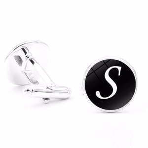 Macro view of silver cufflinks with black round inlay and white letter S design