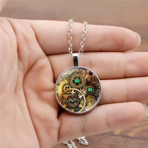 Détail macro du pendentif steampunk avec engrenages vintage et pierres vertes en main