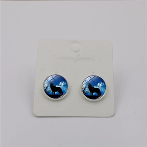 Detailed view of silver-toned round studs featuring a howling wolf and moon glass dome