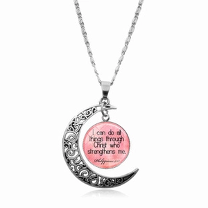 Dettaglio del ciondolo luna in argento con versetto Phil 4:13 su sfondo rosa