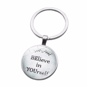 Macro detail of silver keychain with BElieve in YOUrself motivational quote and glass dome