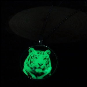 Luminous tiger head pendant necklace glowing green in dark, showing unique glass details