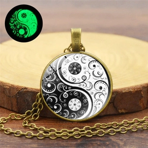 Glow-in-the-dark Yin Yang mandala pendant necklace shown on a rustic wood background