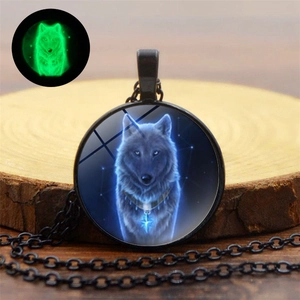 Macro detail of a glowing wolf pendant showing fluorescent effect on a wooden texture