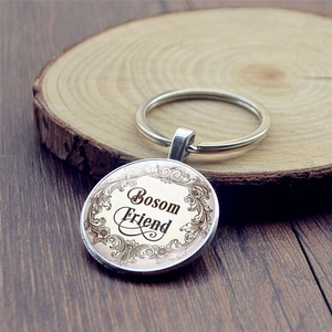 Vintage silver metal keychain with Bosom Friend engraving and floral frame on wood
