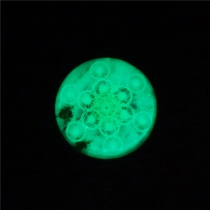 Détail du pendentif mandala lumineux vert avec motif de géométrie sacrée dans le noir