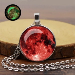 Détail macro du collier lune en argent avec pendentif lune de sang luminescent sur bois