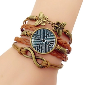Détail du bracelet bohème multicouche en cuir avec papillon en bronze et signe infini