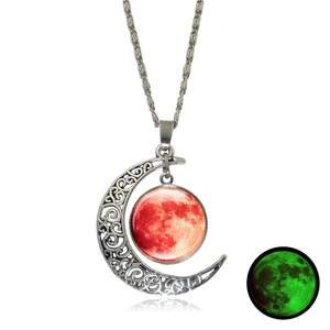 Detail of silver crescent moon necklace with a glowing red stone featuring green luminescent effect