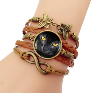 Détail macro du bracelet bohème multicouche en cuir avec pendentif chat et symbole infini