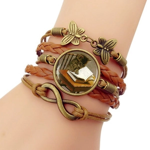 Detail of vintage multilayer braided leather bracelet with dragonfly and infinity charms