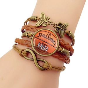 Détail d'un bracelet tissé multicouche avec papillon en bronze, signe infini et motif basket