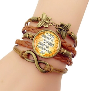 Detail of multi-layer brown leather wrap bracelet with infinity symbol and dragonfly pendant