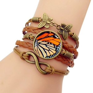 Detail of vintage multilayer leather bracelet with bronze butterfly charms and monarch wing
