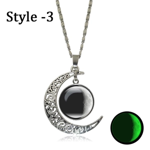 Detailed view of silver crescent moon pendant showing hollow patterns and green glow effect
