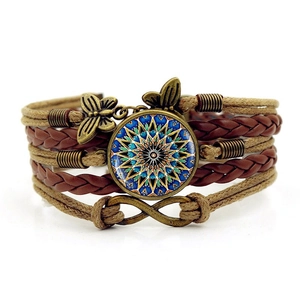 Vue macro d'un bracelet bohème en cuir tressé avec breloque mandala et symbole de l'infini
