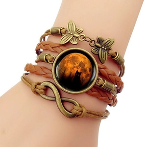 Detail of multi-layer woven leather bracelet featuring bronze charms and black cat gem