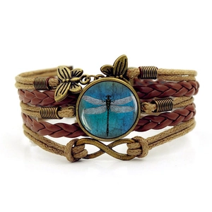 Detailed view of bohemian multilayer bracelet with dragonfly glass cabochon and leather cords