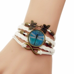 Detail of bohemian multilayer white braided bracelet with bronze dragonfly and infinity charms