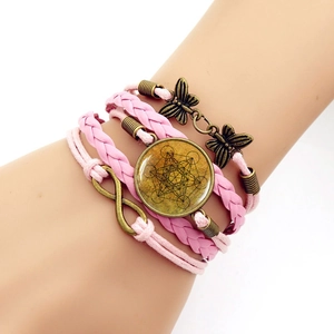 Macro view of multi-layer pink leather bracelet with infinity and butterfly charms