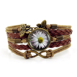 Dettaglio del bracciale vintage in pelle intrecciata multistrato con margherita e farfalle