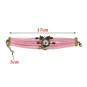 Dettaglio del bracciale intrecciato multistrato rosa con ciondolo margherita e farfalla