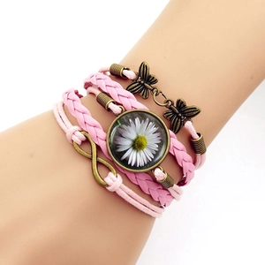 Dettaglio bracciale rosa intrecciato con farfalla, simbolo infinito e cabochon in vetro margherita