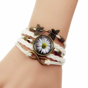 Dettaglio del bracciale in pelle intrecciata con farfalle in bronzo e simbolo dell'infinito